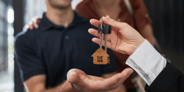 A smiling couple receiving keys to their new home after completing proof of funds, symbolising a successful property purchase.