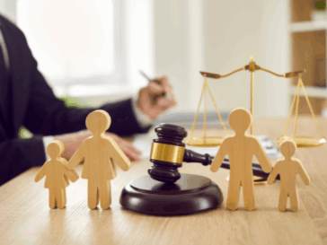 Wooden family figures with a gavel and scales of justice in the background, symbolising child court applications and family law.