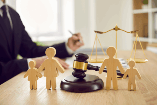 Wooden family figures with a gavel and scales of justice in the background, symbolising child court applications and family law.