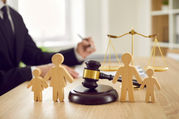Court Application for a Child – Family Law and Child Arrangements Orders Wooden family figures with a gavel and scales of justice in the background, symbolising child court applications and family law.
