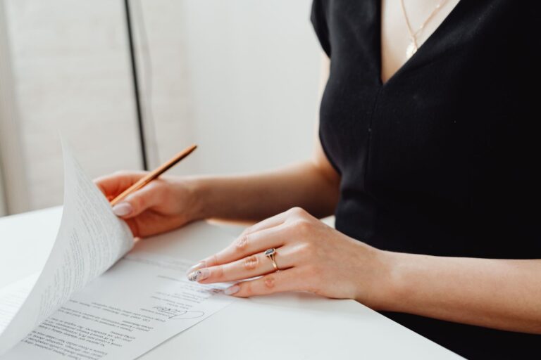 Woman in black reviewing signed Lasting Power of Attorney document at desk before sending to the Office of the Public Guardian.