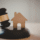 Wooden auction gavel next to a small house-shaped cutout on a sound block, representing buying a property at auction.
